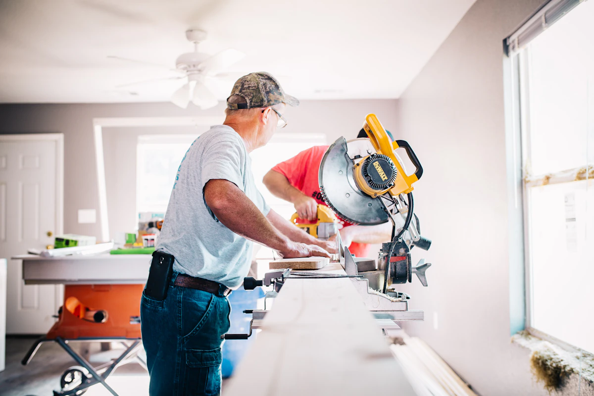 Charpentier de l'atelier Chalet Modulaire découpant une pièce d'épicéa en atelier