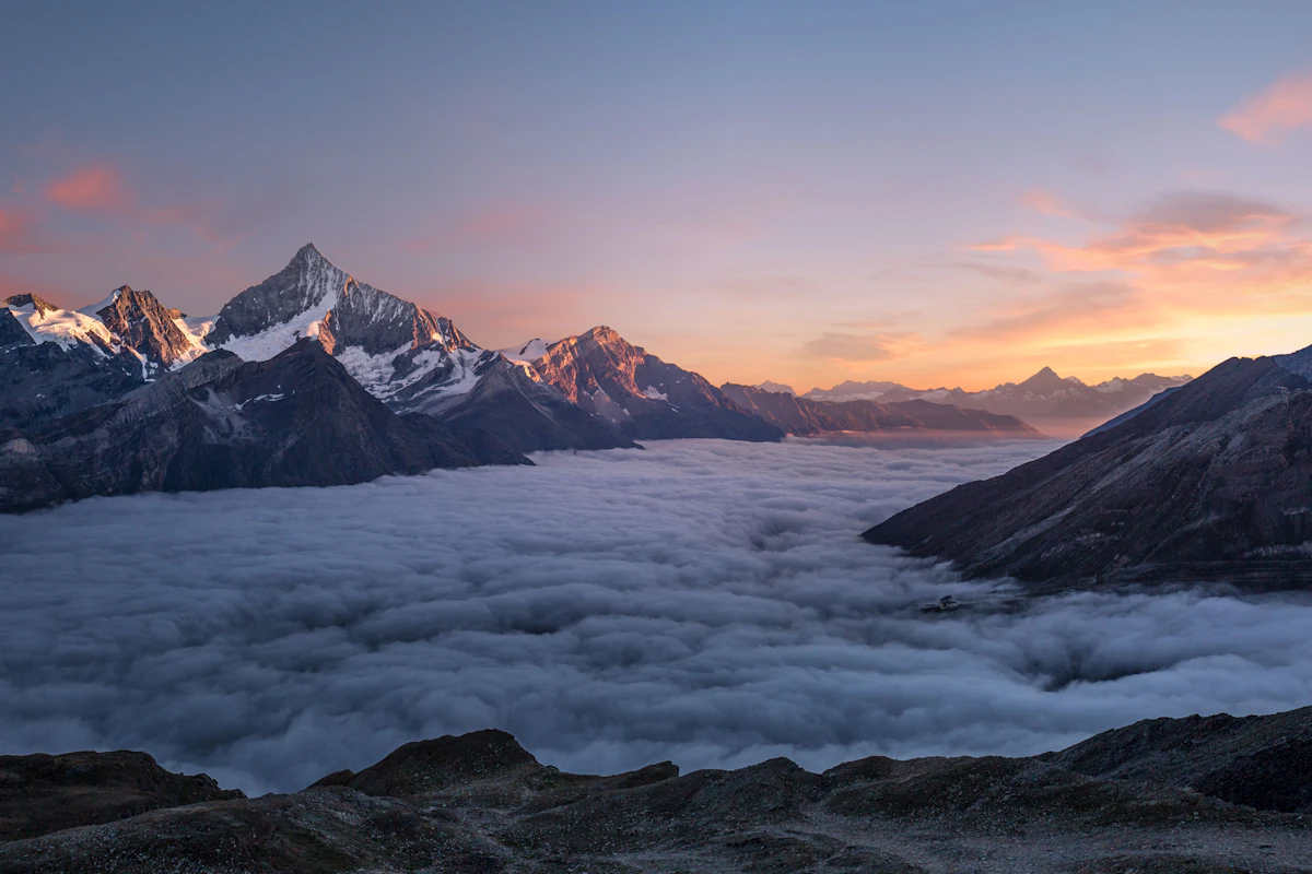 Mer de nuages sous les sommets au lever du soleil